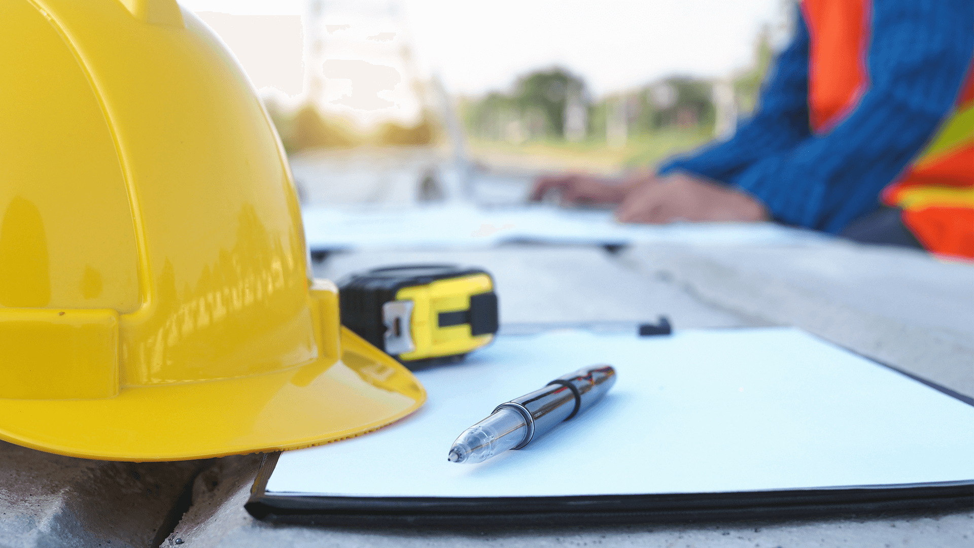 contractor’s checklist under his hard hat and measuring tape on a construction site